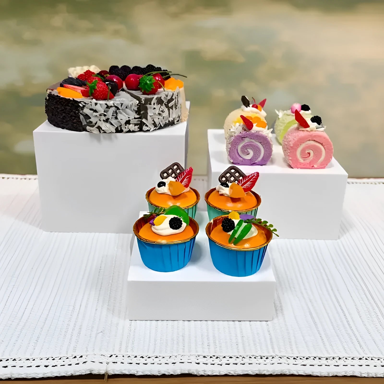 White and transparent plastic cube dessert display stands arranged in a tiered set.