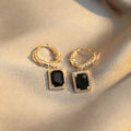 A pair of geometric copper earrings with black zircon stones in a quadrilateral shape.