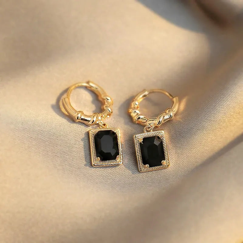 A pair of geometric copper earrings with black zircon stones in a quadrilateral shape.