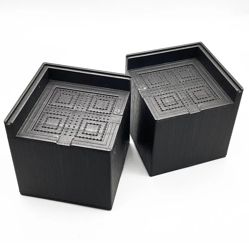 Four black circular plastic foot mats for furniture height increasing.