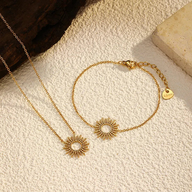 Gold geometric chain necklace and matching bracelet set on a plain background.