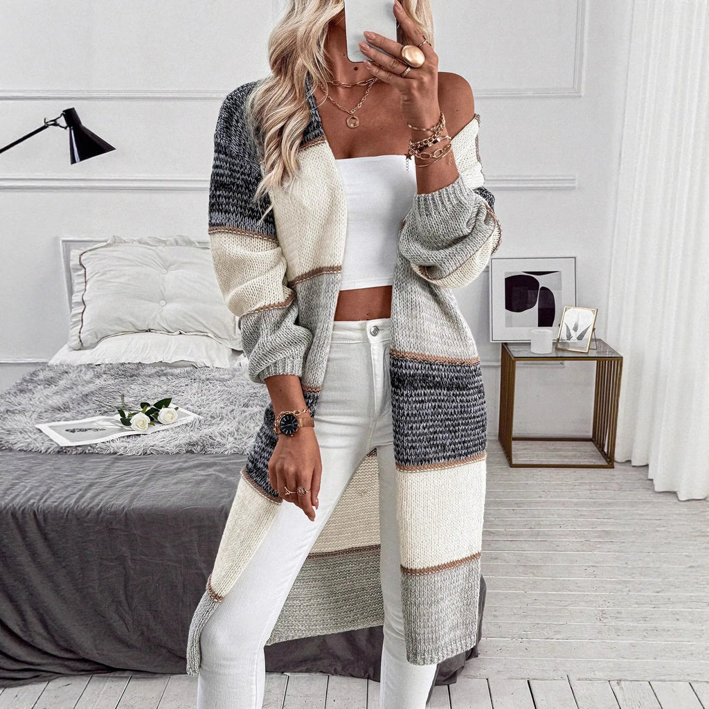 Grey women's knitted long cardigan with loose fit and long sleeves on a hanger.