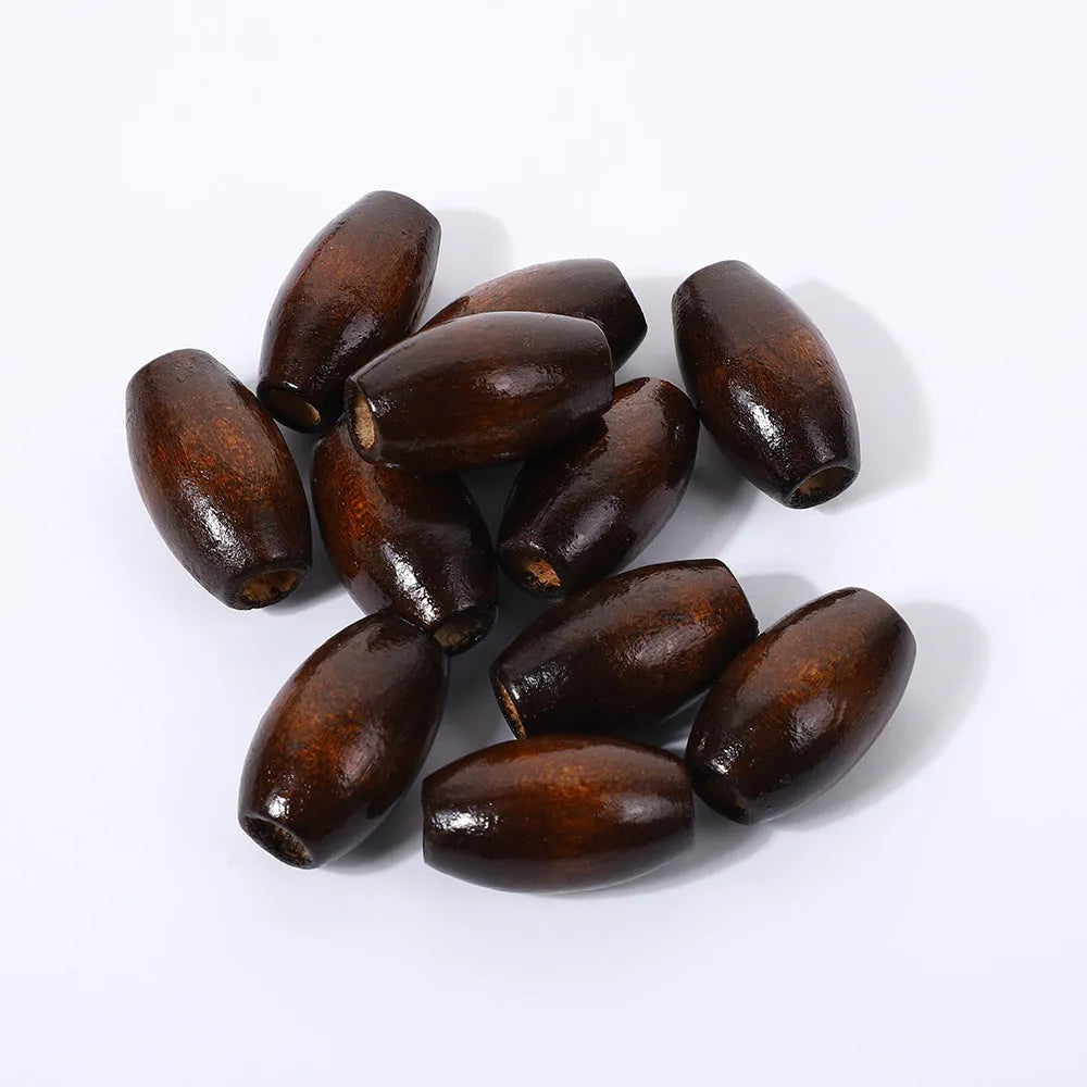 Dark coffee coloured oval wooden bead with a raised M-shaped design, showing scale.