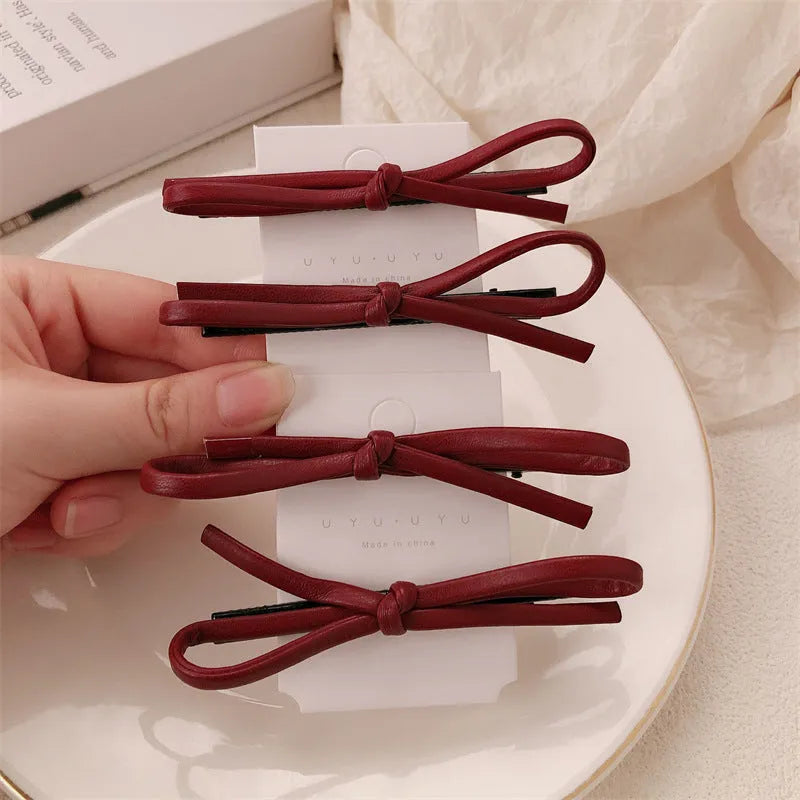 Wine red leather hair clip with a classic bow design on a white background.