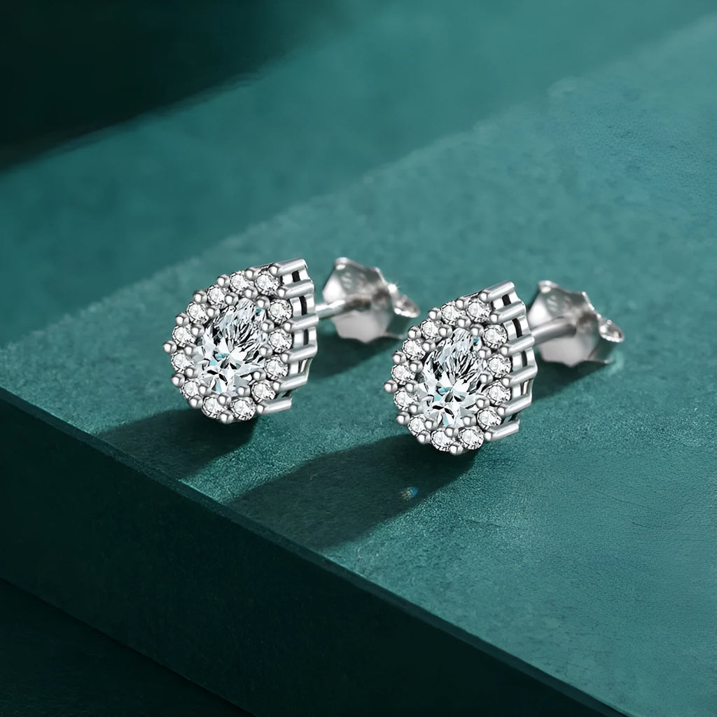 Close-up of a pair of women's silver water drop shaped ear studs on a plain background.