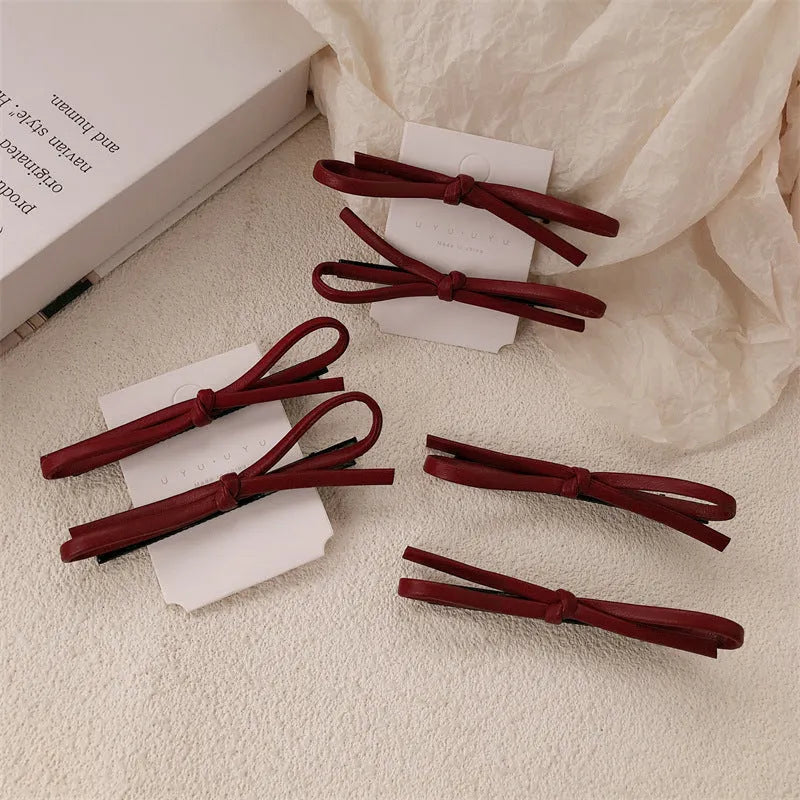 Wine red leather hair clip with a classic bow design on a white background.