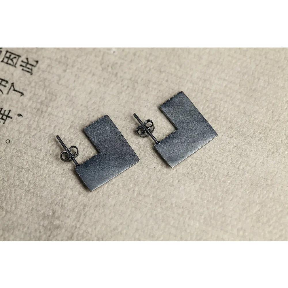Close-up of a pair of oxidation black geometric square stud earrings made from 925 sterling silver.