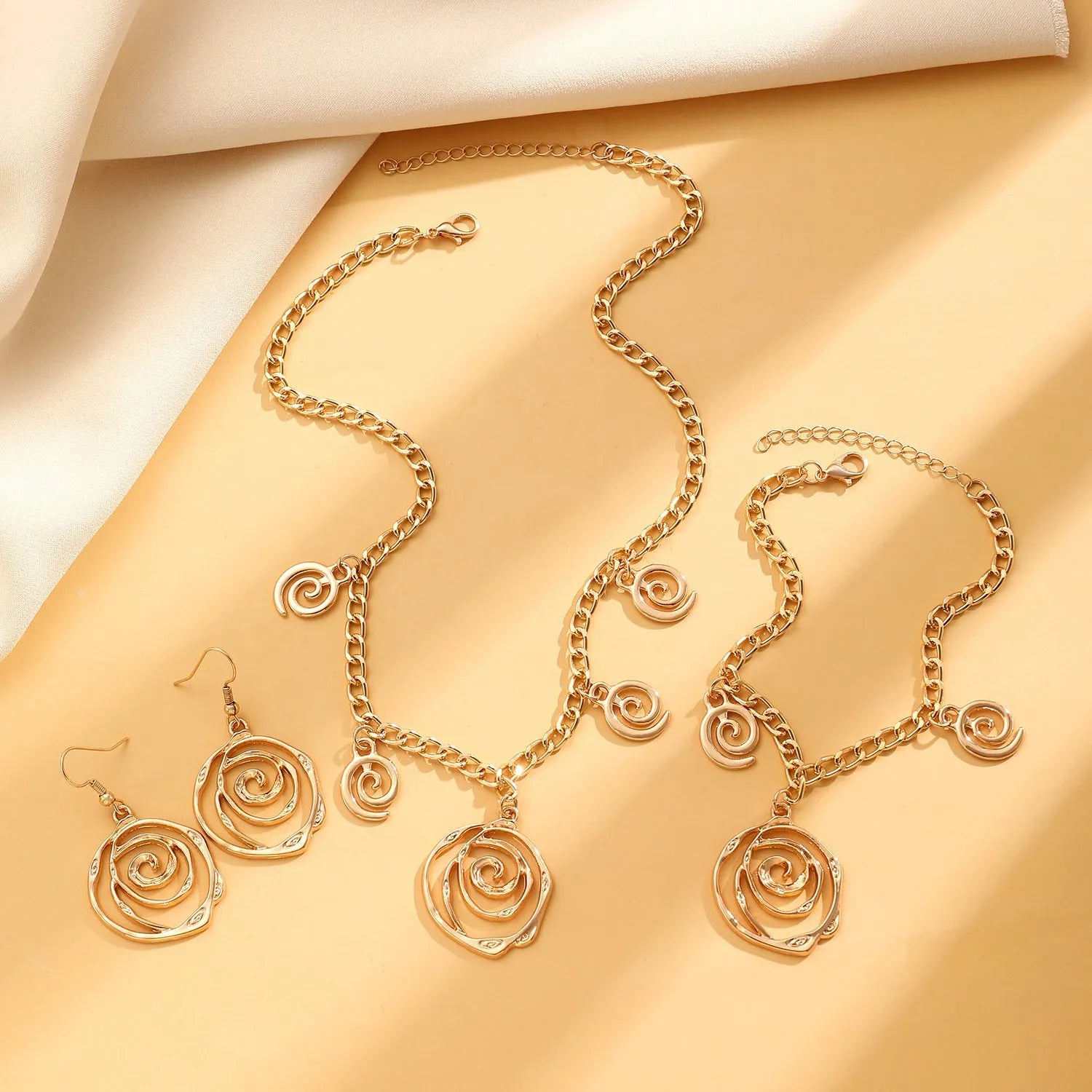 Spiral donut jewellery set showing necklace, bracelet, and earrings in geometric circle design with gold finish