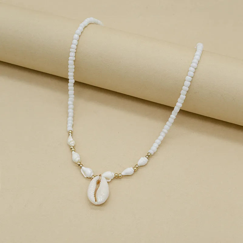 White conch shell bead necklace with a detailed mother pearl shellfish pendant on a regular chain.
