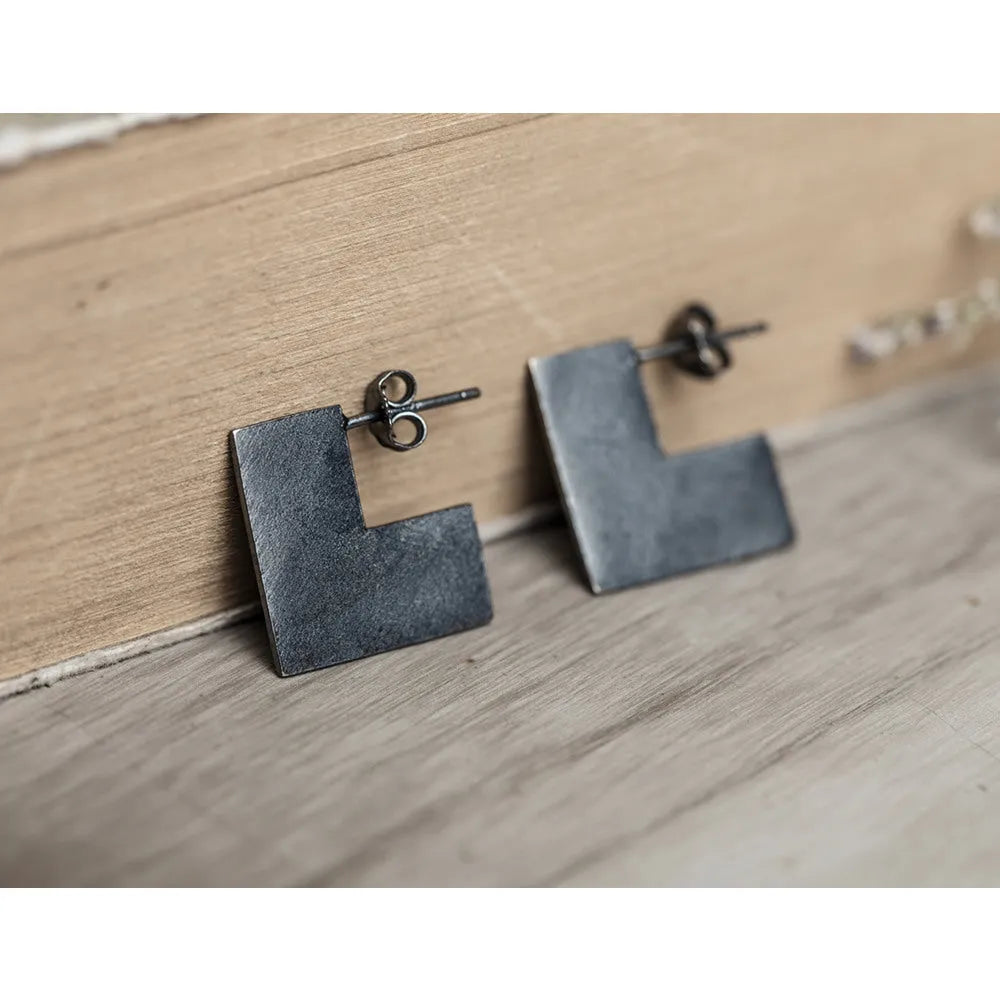 Close-up of a pair of oxidation black geometric square stud earrings made from 925 sterling silver.