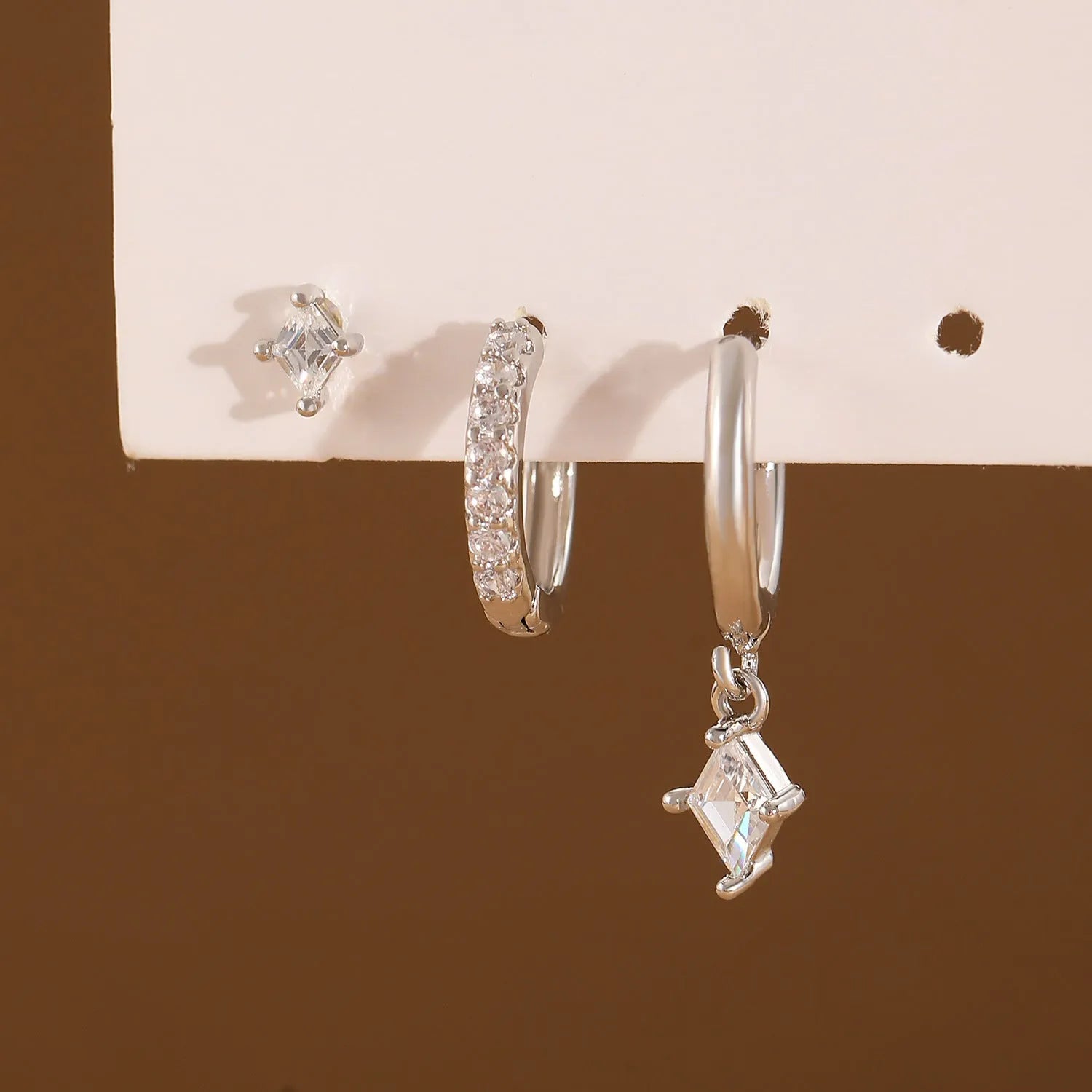 Geometric zircon three-piece earring set showing pendant, stud, and clip styles in gold finish