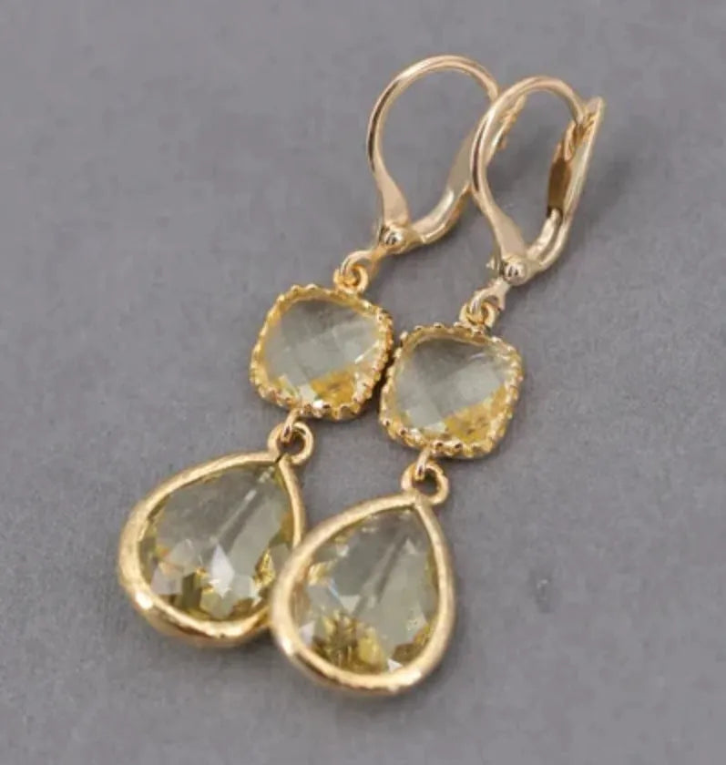 Gold geometric fringe earrings with crystal water droplet details on white background