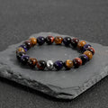 Minimalist elastic bracelet with a geometric natural tiger-eye stone in yellow, purple, or red.