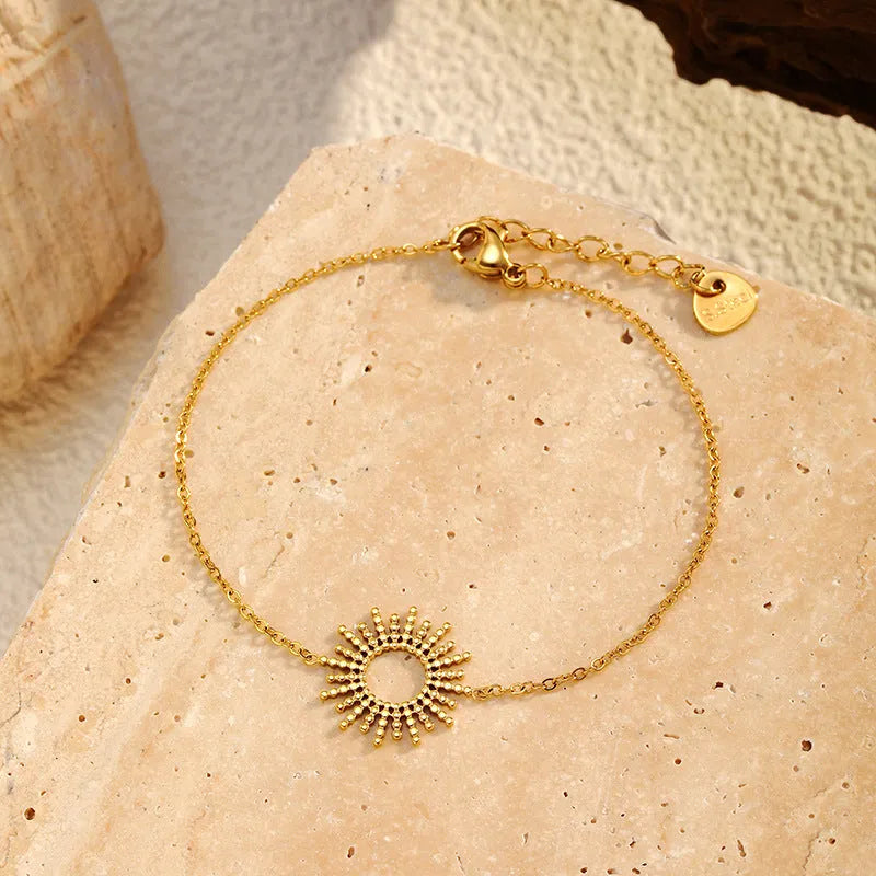 Gold geometric chain necklace and matching bracelet set on a plain background.
