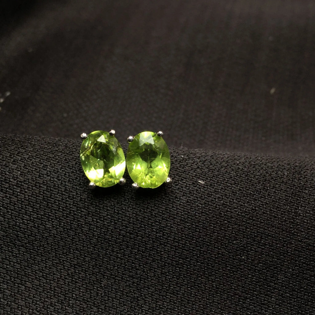 Grass green natural olivine oval stud earrings in sterling silver on a white background.