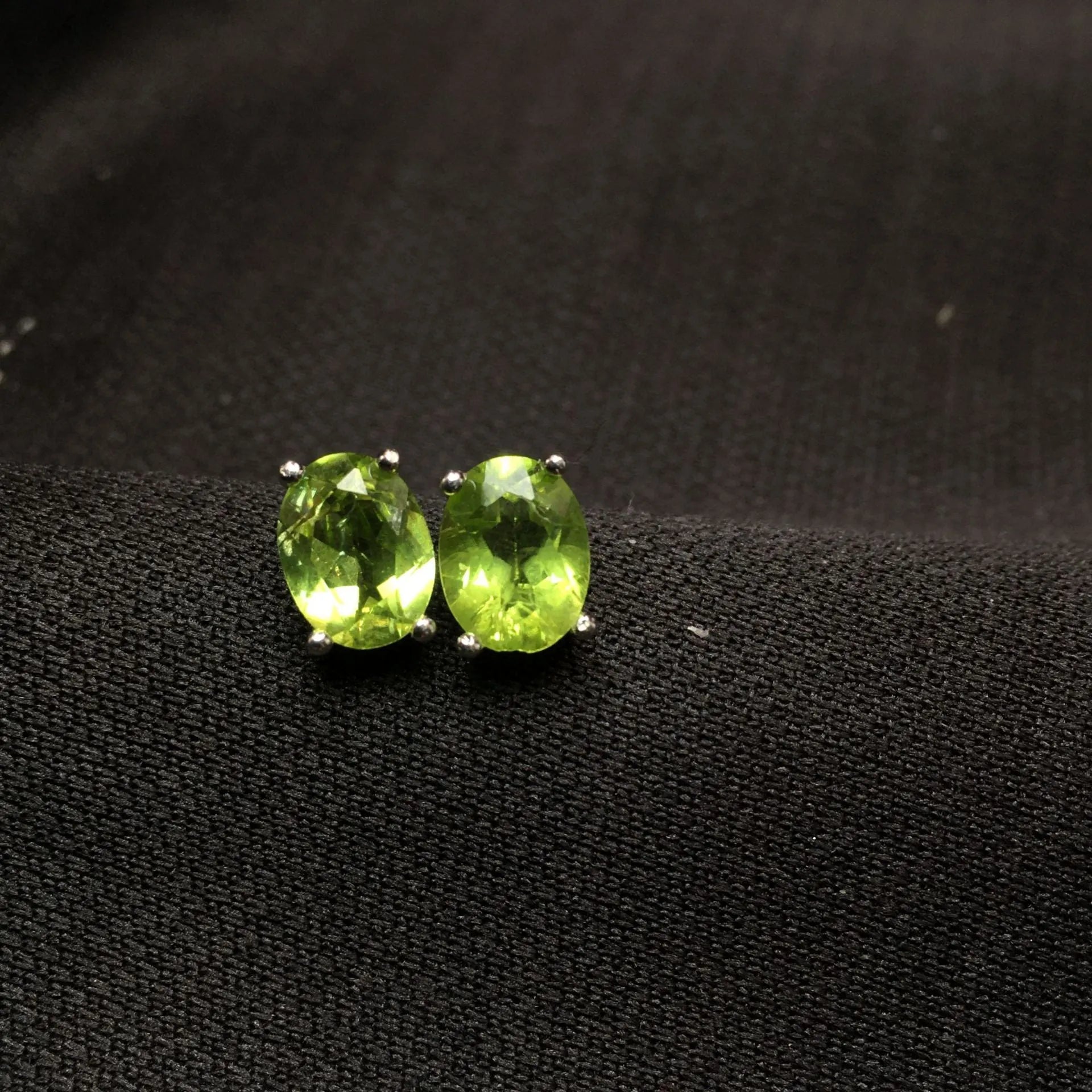 Grass green natural olivine oval stud earrings in sterling silver on a white background.