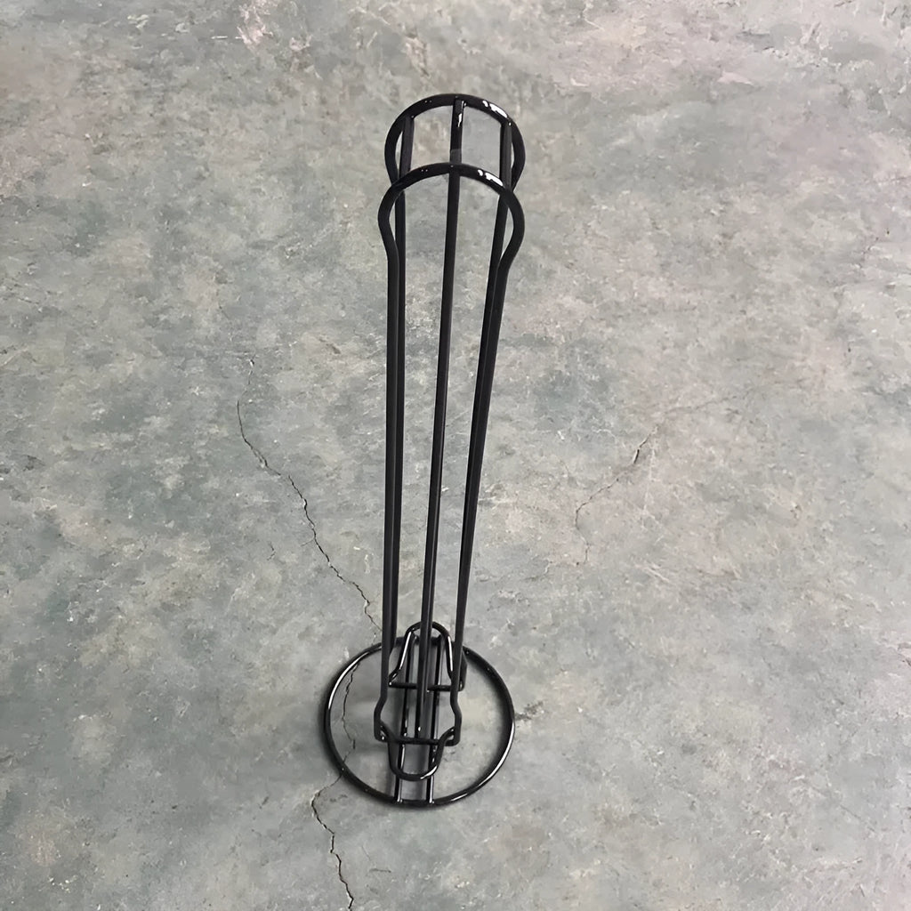 A black wrought iron coffee capsule storage rack holding pods on a kitchen counter.
