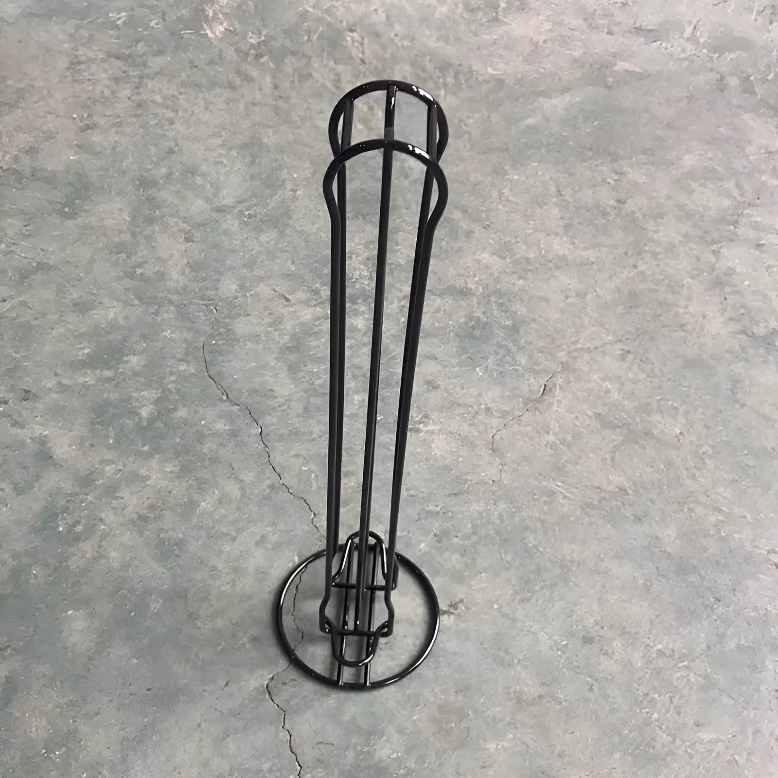 A black wrought iron coffee capsule storage rack holding pods on a kitchen counter.