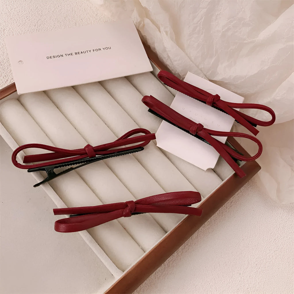 Wine red leather hair clip with a classic bow design on a white background.