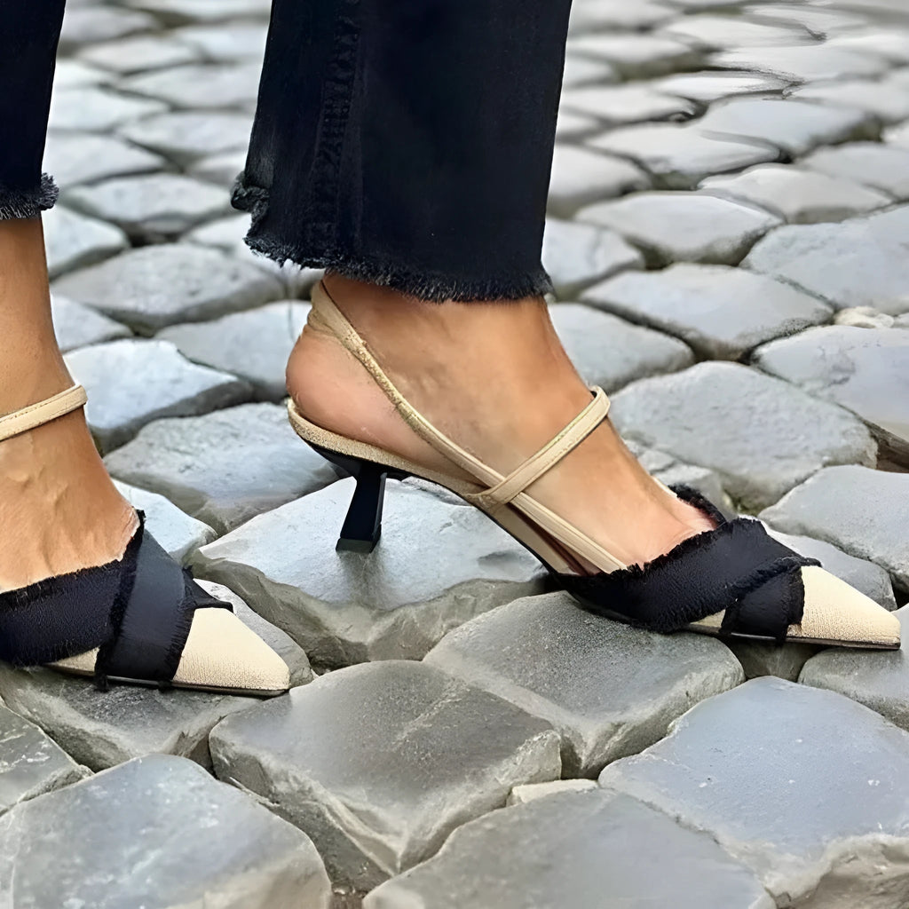 Apricot and black women's stiletto sandals with a pointed toe and buckle fastening on a white background.
