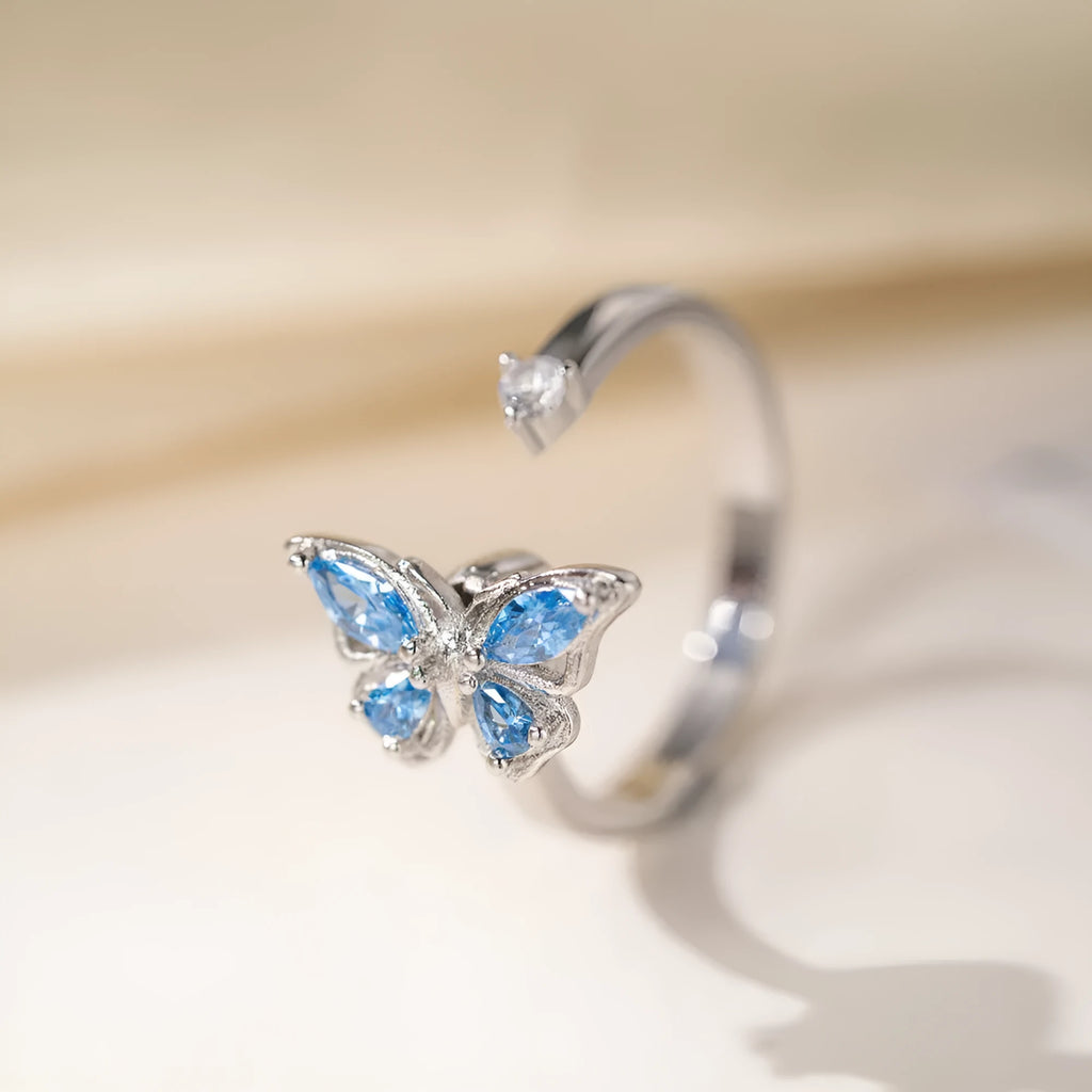 Butterfly adjustable ring with electroplated white gold finish and blue diamond accent on copper base