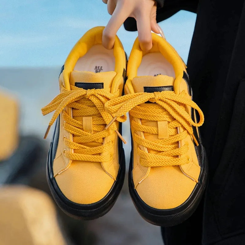 Women's low-top board shoes in a black and white colour combination, showing round toe and front lace-up design.