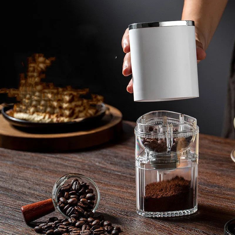 White portable electric coffee grinder with USB charging cable on a wooden table