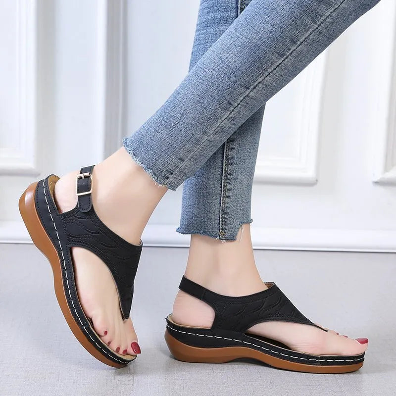 Women's red wedge heel sandals with an adjustable buckle strap on a plain background.
