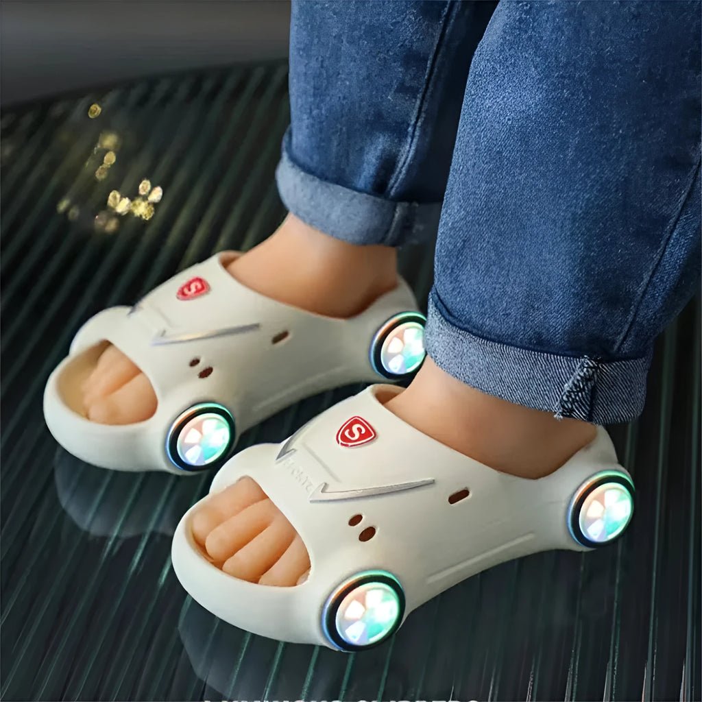 Kids luminous cartoon car slippers flashing blue, with anti-slip sole texture visible.