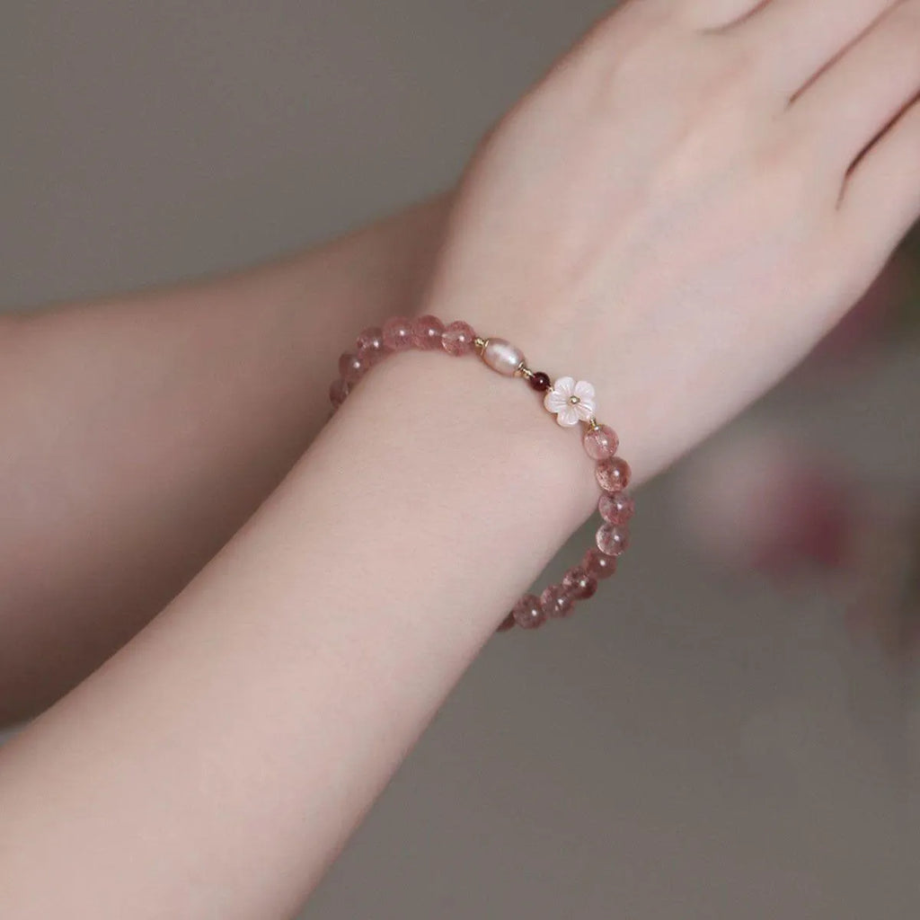 Strawberry quartz crystal bracelet with a peach blossom flower shape on a wrist.