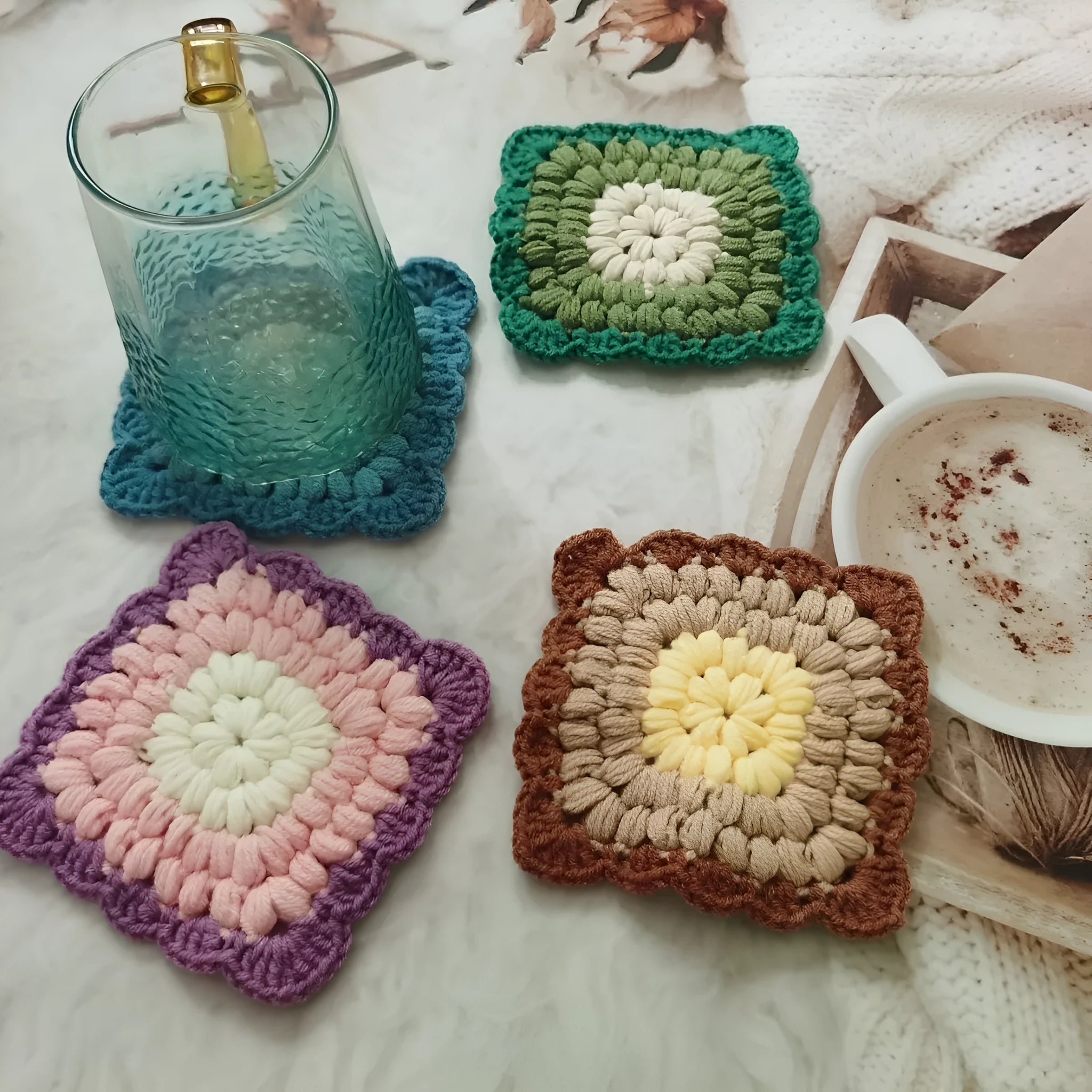 Handmade crocheted wool cup placemat with a grandmother lattice design on a wooden table.