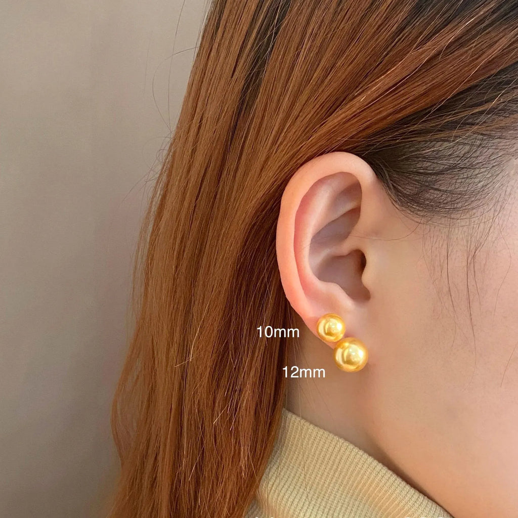 A pair of large geometric silver stud earrings with a central pearl and an eight-point star design detail.
