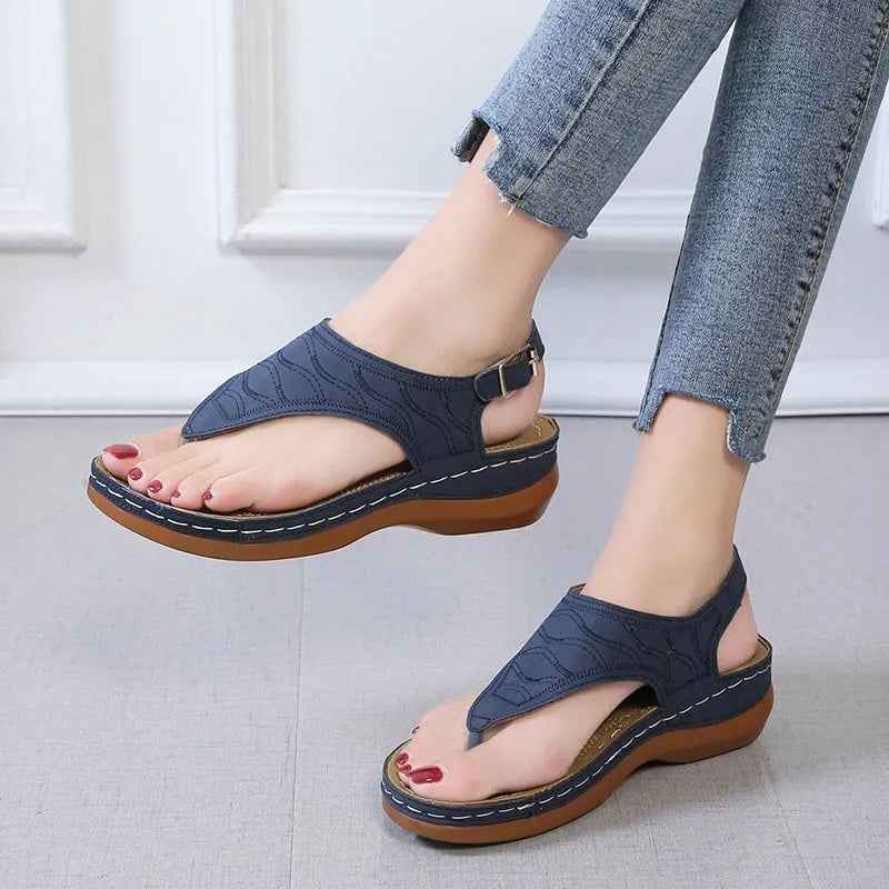 Women's red wedge heel sandals with an adjustable buckle strap on a plain background.