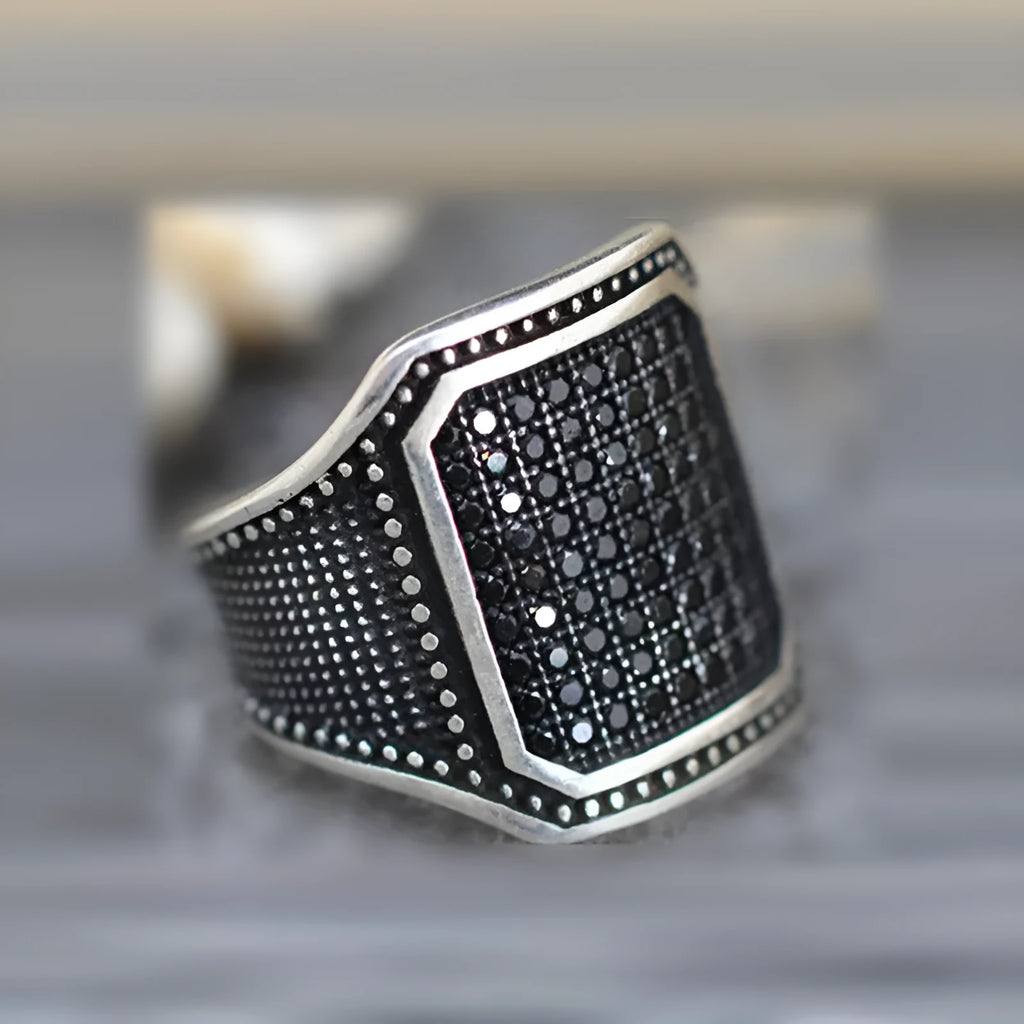 Black alloy ring with copper inlay and zircon detailing on a finger, showing ring sizes 7 to 13.
