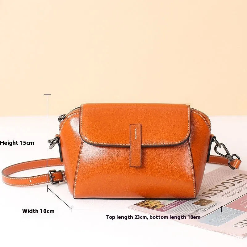 Brown leather women's crossbody messenger bag showing shell shape and visible stitching.