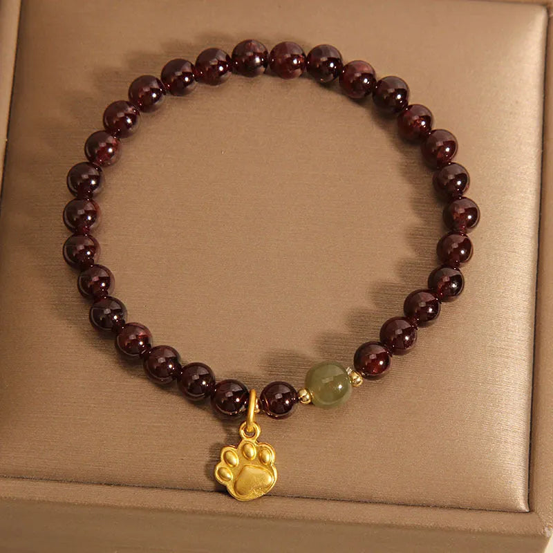 Women's adjustable crystal bracelet with a cat's paw shaped garnet stone centrepiece.