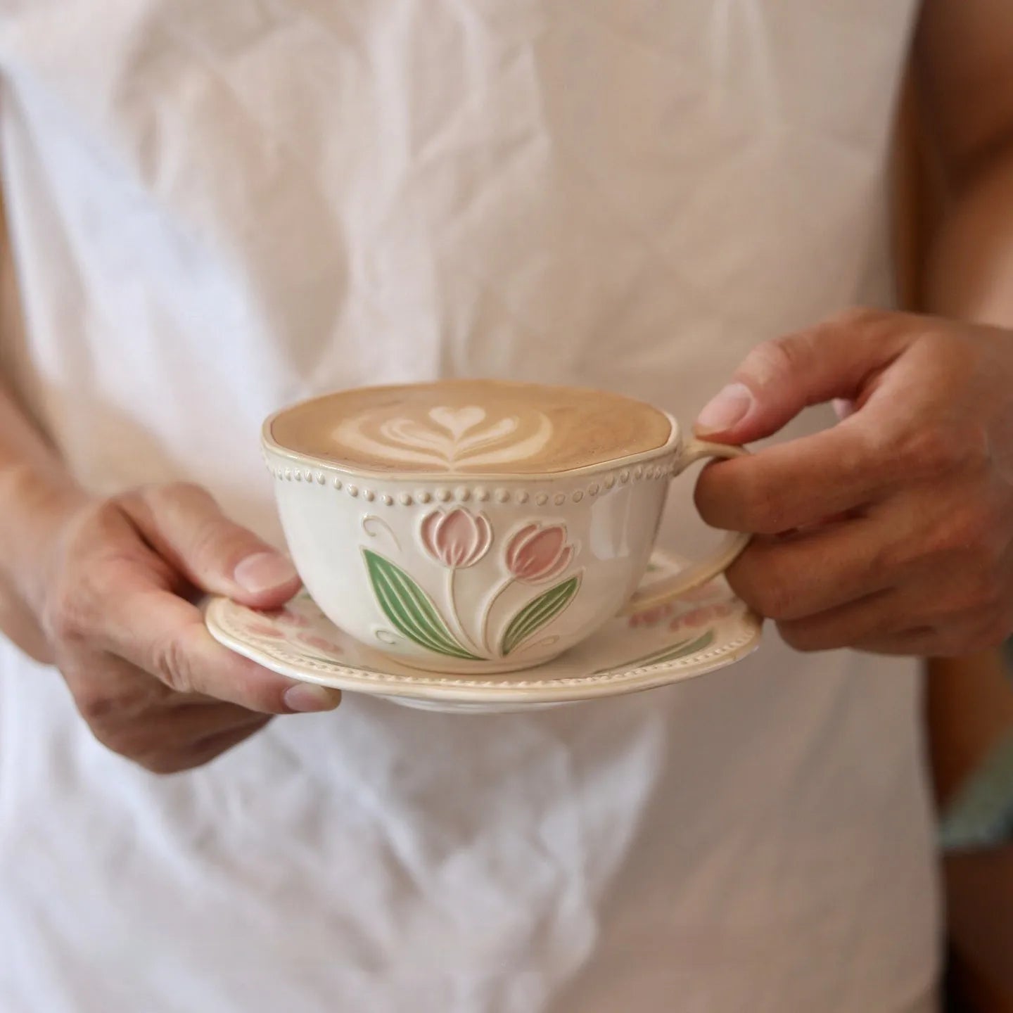 Ceramic tulip carved flower retro steam pitcher with curved handle and saucer on a table