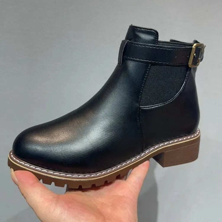 Black ankle boots with round toe and belt buckle decoration, showing rubber sole and waterproof artificial PU upper