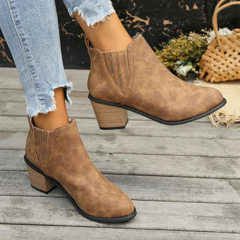 Women's black pointed toe ankle boots with thick square low heel on wooden floor