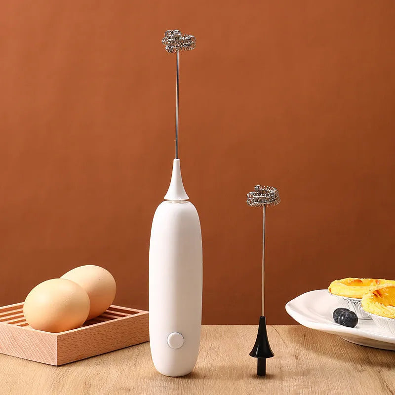 Black and white electric hand-held milk frother for coffee preparation on kitchen counter