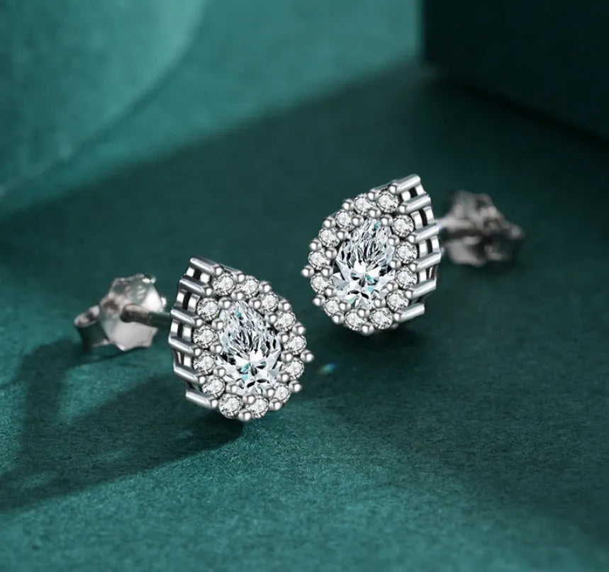 Close-up of a pair of women's silver water drop shaped ear studs on a plain background.