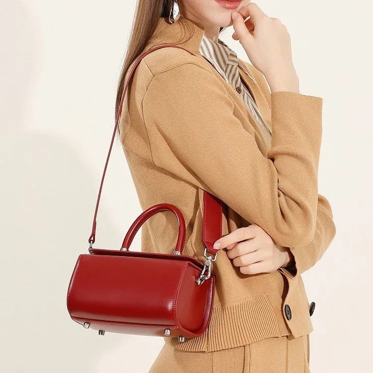 Women's black cowhide leather one-shoulder crossbody bag with clamshell opening, shown closed.