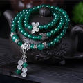 Close-up of a women's multi-strand bracelet with green agate beads on a wrist.