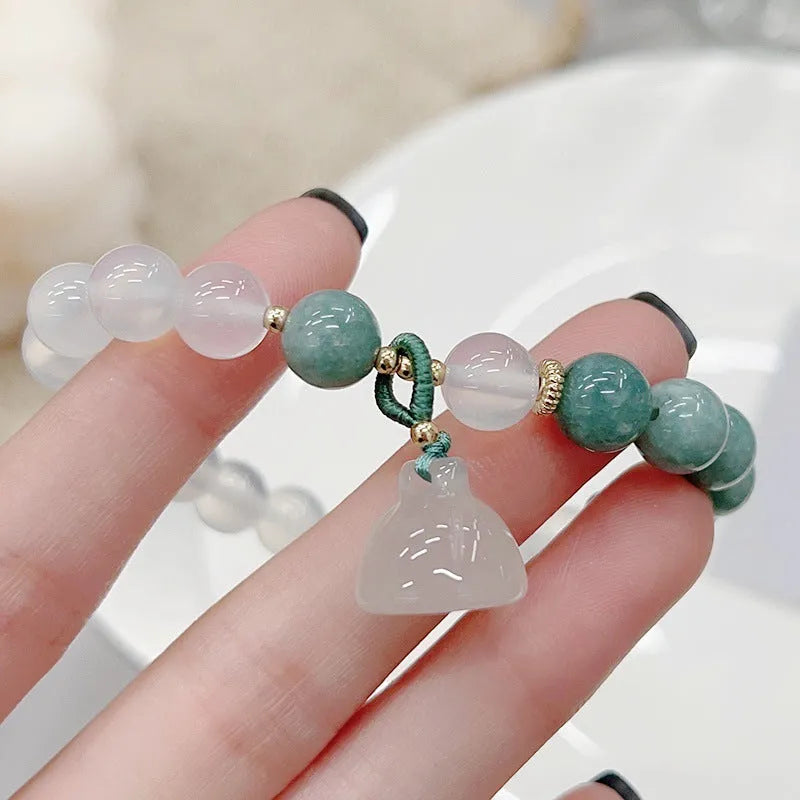 Close-up of a retro-style agate bracelet with a carved lotus seedpod design on a wrist.