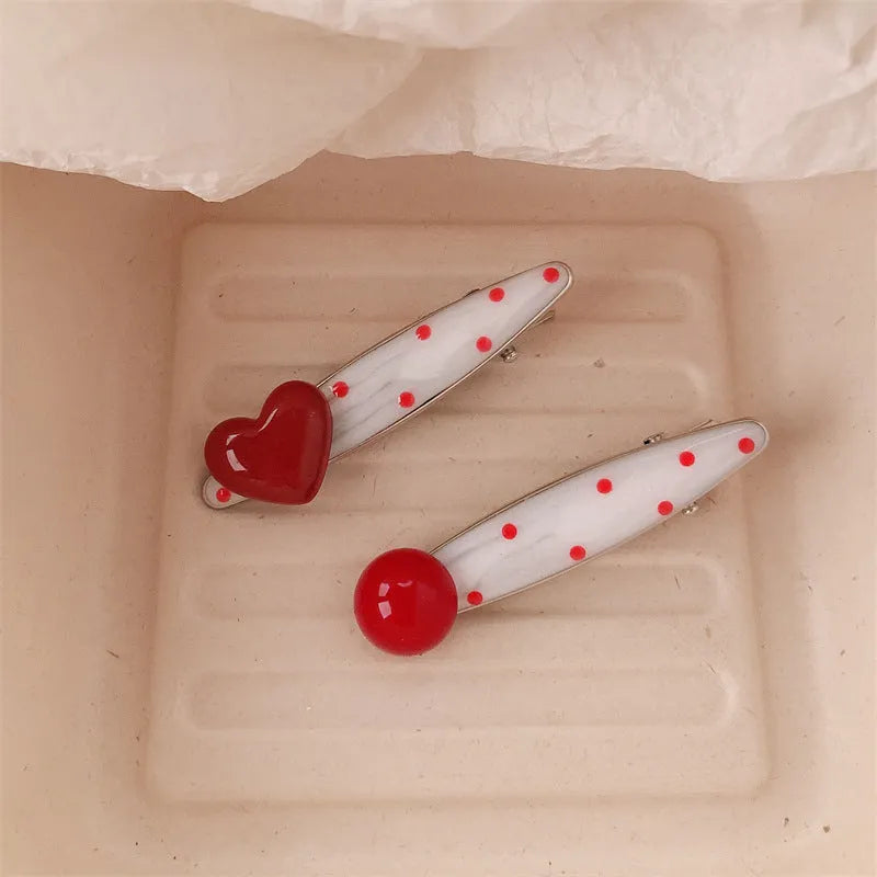 Red love heart-shaped hair clip with white polka dots and a green willow leaf decoration.