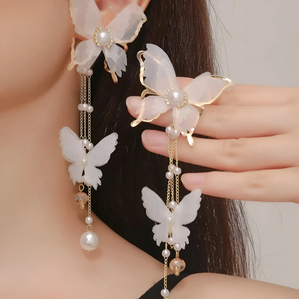 White butterfly-shaped earrings with dangling tassel, lace patterning, pearls, and clear rhinestones.