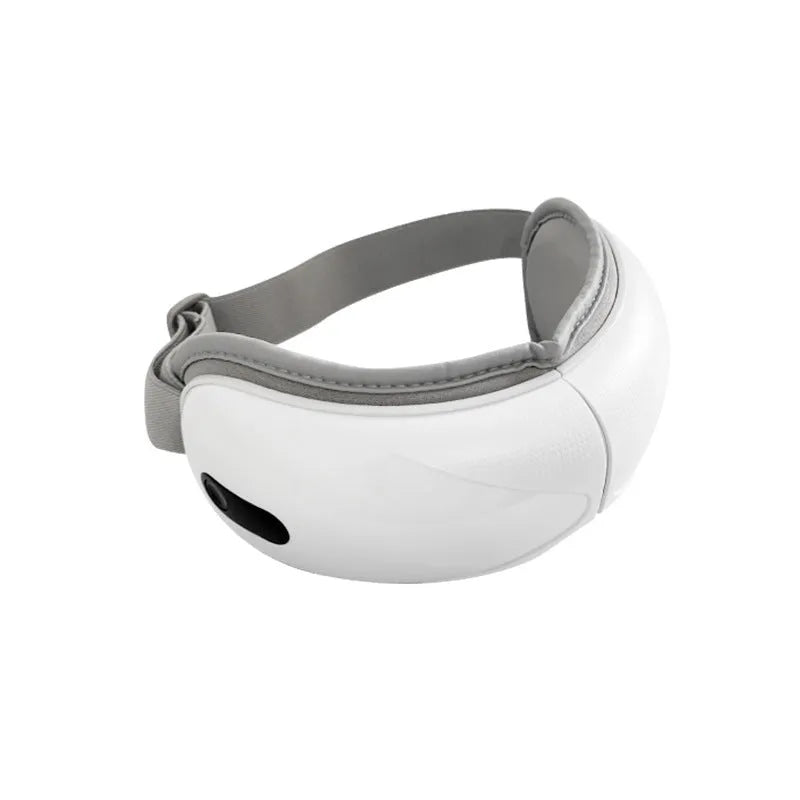 White rechargeable eye massager with hot compress and airbag massage functions on a table.
