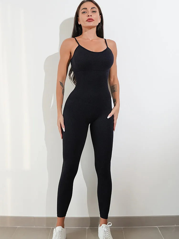 Woman wearing a black sleeveless unitard jumpsuit with spaghetti straps and a backless design.