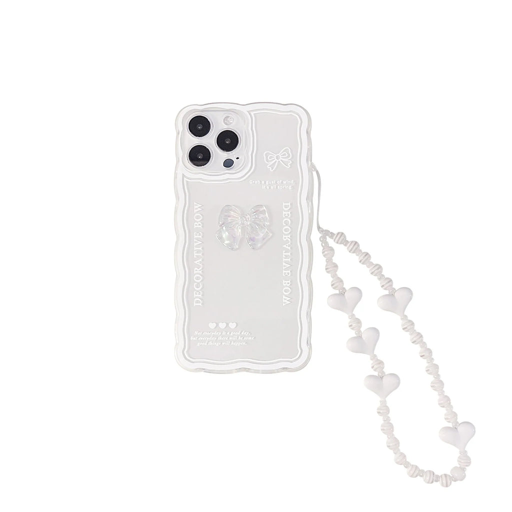 Clear iPhone case with a raised 3D bow design and a white love lanyard on a table.