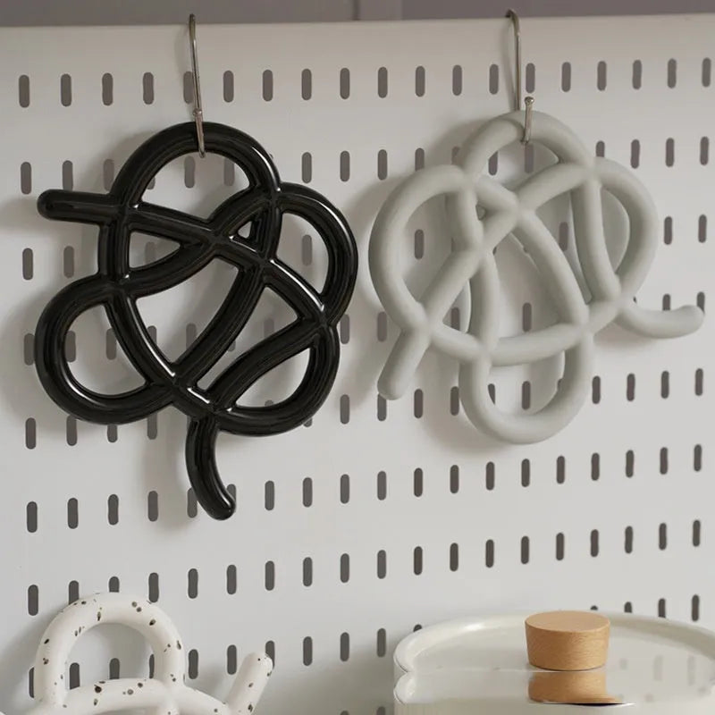 A solid colour ceramic heat proof mat with an irregular shape on a dining table.